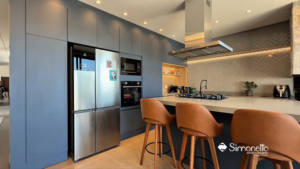 Cozinha planejada Simonetto em azul petróleo com ilha funcional e iluminação embutida sob medida.