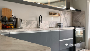 Cozinha planejada com armários cinza fosco e bancadas em mármore claro, design clean e sofisticado